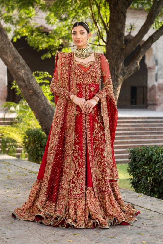 Bride wearing a red bridal lehenga anarkali with heavy gold embroidery and a matching dupatta by Kshkin Bride wearing a red bridal lehenga anarkali with heavy gold embroidery and a matching dupatta by Kshkin