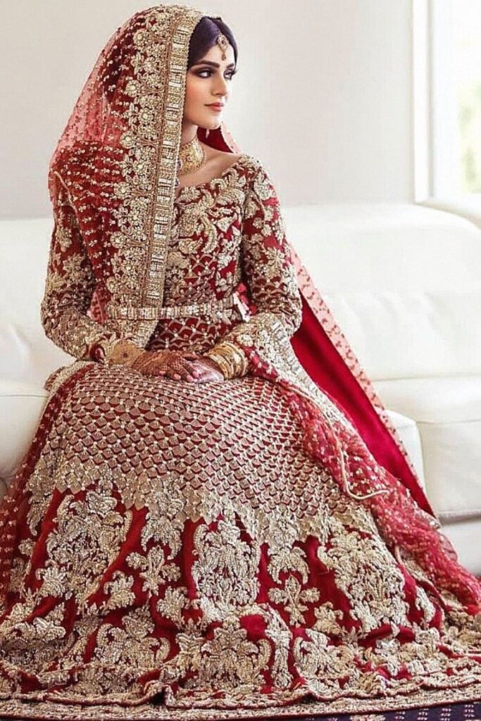 Bride in a red bridal lehenga with heavy gold embroidery and a matching net dupatta Bride in a red bridal lehenga with heavy gold embroidery and a matching net dupatta